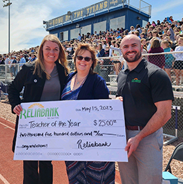 Reliabank employee stands with TAPTO member and Tea Area school district teacher of the year as a check for $2,500 is presented to the teacher.