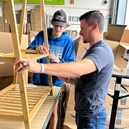 A Reliabank employee and his son assemble a wooden shelf while volunteering at non-profit VOA Greater Goods in Sioux Falls.