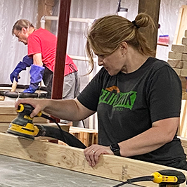 Reliabank employee runs a circular saw while volunteering with non-profit Sleep in Heavenly Peace in Watertown.