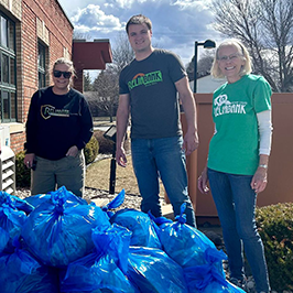 Three Reliabank employees stand in front of several blue garbage bags after a community clean up in Hayti.